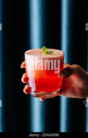 Roter Erdbeer alkoholischer Cocktail in der Hand einer Frau Stockfoto