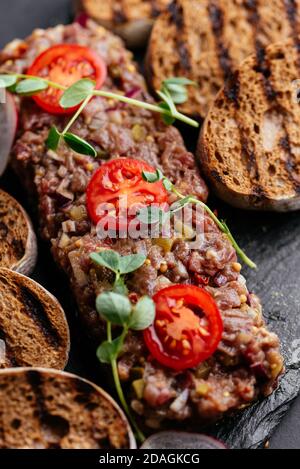 Rindertartare mit Roggencroutons auf schwarzem Hintergrund Stockfoto