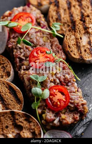 Rindertartare mit Roggencroutons auf schwarzem Hintergrund Stockfoto