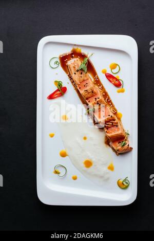 Gegrillter Lachs mit Sauce auf einem weißen Teller Stockfoto