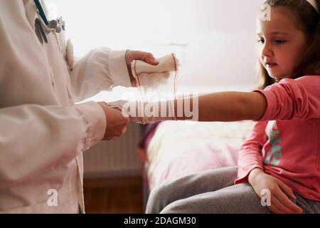 Ärztin verband den Arm eines kleinen Mädchens in ihrem Zimmer. Hausarzt Konzept Stockfoto