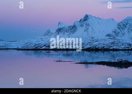 Winterdämmerung leuchtet über den Bergen von Flakstadøy, Lofoten Inseln, Norwegen Stockfoto