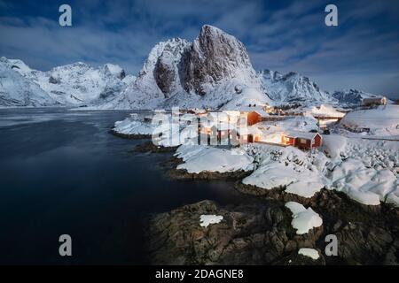 Vollmond beleuchtet schneebedeckte Landschaft und Dorf Hamnøy, Moskenesøy, Lofoten Inseln, Norwegen Stockfoto