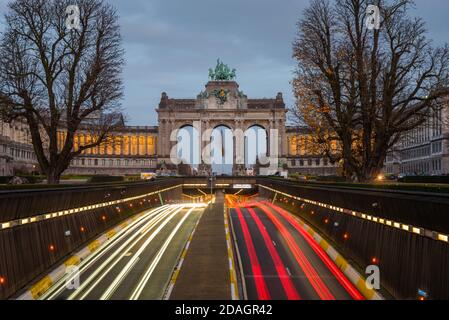 Offener Abschnitt einer Straße, die unter dem Park du Cinquantenaire im Zentrum von Brüssel, Belgien, in der Abenddämmerung führt. Leichte Wanderwege. Stockfoto