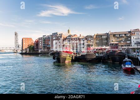 Blick auf die Skyline von Portsmouth an einem sonnigen Herbsttag. Drei festgetäute Schlepper stehen im Vordergrund. Stockfoto