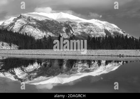 Monochrome oder Schwarzweiß-Landschaftsaufnahme des Snowy Mountain Peak, reflektiert im ruhigen und kalten Wasser des Sees über Canmore, Alberta, Kanadische Rockies Stockfoto