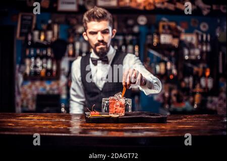 Junge Barkeeper mixen einen Cocktail, während sie in der Nähe der Bar stehen Zähler in Bar Stockfoto