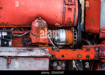 Nahaufnahme des Vierzylinder-Dieseltraktormotors mit sichtbarem Gurt Rosty verfolgt hydraulische Teile und Verdrahtung rote Farbe in sonnigen Herbsttag Stockfoto