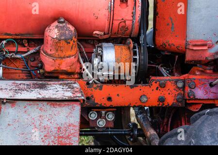 Nahaufnahme des Vierzylinder-Dieseltraktormotors mit sichtbarem Gurt Rosty verfolgt hydraulische Teile und Verdrahtung rote Farbe in sonnigen Herbsttag Stockfoto