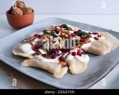 Knödel auf einem Teller mit Nüssen, Schokolade bestreut und mit frischen Minzblättern verziert Stockfoto