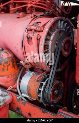 Nahaufnahme des Vierzylinder-Dieseltraktormotors mit sichtbarem Gurt Rosty verfolgt hydraulische Teile und Verdrahtung rote Farbe in sonnigen Herbsttag Stockfoto