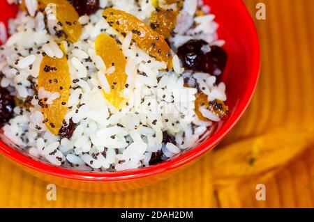 Handgemachte Zubereitung von Leckereien für traditionelle orthodoxe Weihnachten - Reispudding mit Früchten, Preiselbeeren, Honig, Nüssen, Kirchenkerzen Stockfoto