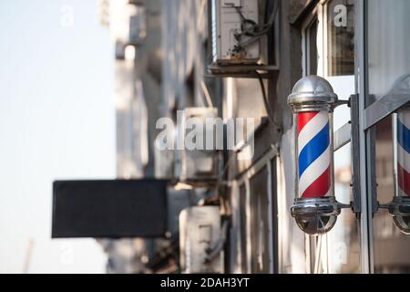 Typisch amerikanische Barbiere stehen vor einem Friseurladen. Dieser Stock ist ein Vintage-Zeichen, das die Anwesenheit eines männlichen Friseursalon anzeigt. Bild Stockfoto