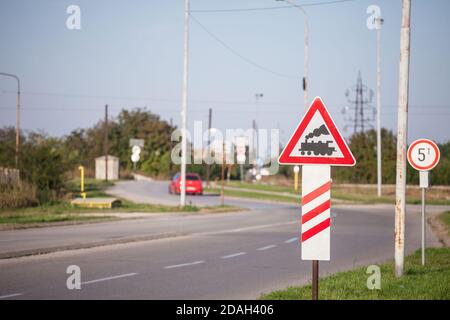 Typisches europäisches Bahnübergangsschild auf einer Landstraße, das bald einen unbewachten Bahnübergang anzeigt, mit seiner ikonischen schwarzen Dampflokomotive auf einem roten T Stockfoto