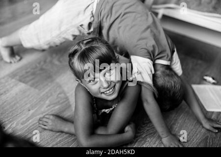 Kleines Mädchen schelmisch spielt mit ihrem Bruder. Schwarzweiß-Fotografie. Stockfoto