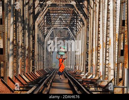 Mumbai, Indien. November 2020. Eine Frau, die Gepäck trägt, läuft auf der Eisenbahnstrecke.Menschen benutzen die Brücke der Eisenbahnstrecke über dem Bach und riskieren ihr Leben jeden Tag. Kredit: SOPA Images Limited/Alamy Live Nachrichten Stockfoto