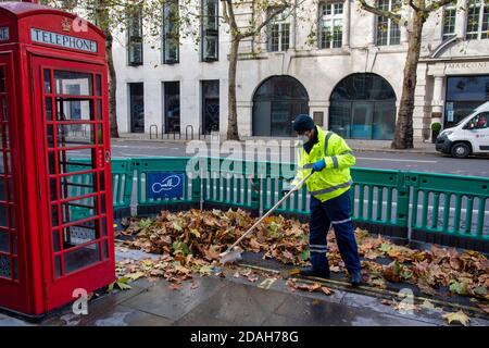 London, Großbritannien. November 2020. Ein Mitarbeiter des Westminster council fegt im Londoner Aldwych herbei gefallene Blätter. Kredit: SOPA Images Limited/Alamy Live Nachrichten Stockfoto