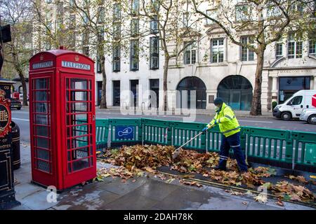 London, Großbritannien. November 2020. Ein Mitarbeiter des Westminster council fegt im Londoner Aldwych herbei gefallene Blätter. Kredit: SOPA Images Limited/Alamy Live Nachrichten Stockfoto