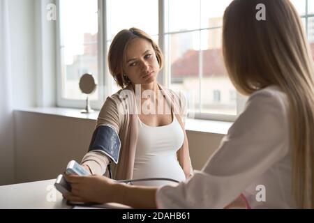 Arzt messen Blutdruck von ihrer schwangeren Patientin Stockfoto