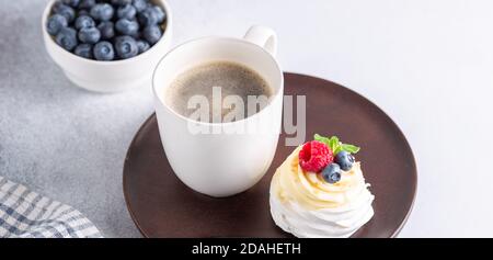 Romantisches Frühlingsfrühstück. Köstliche Pavlova Kuchen mit Sahne und frischen Beeren und Tasse mit Kaffee. Weichfokus - Bild Stockfoto