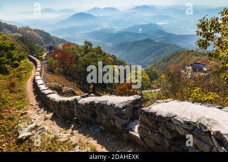 Wunderschöne koreanische Herbstlandschaft. Bunte Herbstblätter von der Spitze des Berges und traditionelle Gebäude entlang der Burgstraße gesehen. Stockfoto