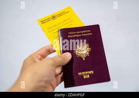 In dieser Abbildung hält die Hand einer Person eine Impfkarte der Weltgesundheitsorganisation und einen französischen Pass. Stockfoto