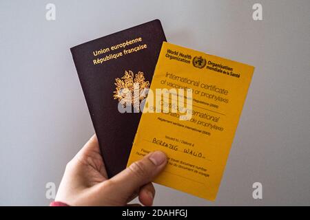 In dieser Abbildung hält die Hand einer Person eine Impfkarte der Weltgesundheitsorganisation und einen französischen Pass. Stockfoto