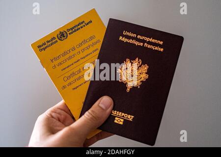 In dieser Abbildung hält die Hand einer Person eine Impfkarte der Weltgesundheitsorganisation und einen französischen Pass. Stockfoto