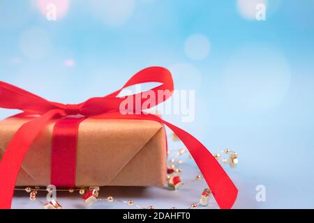 Vorderansicht der Geschenkbox mit roter Schleife auf festlichem blauem Hintergrund mit goldenem Glanz und Copyspace für Ihren Text. Weihnachten, Neujahr Stockfoto
