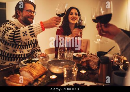 Fröhliche Familie, die Wein toasting und genießen Abendessen am Heiligabend. Familie mit einem Weihnachtsessen zusammen. Stockfoto