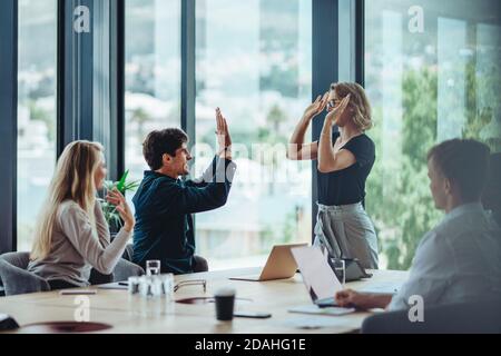 Zwei Kollegen geben bei der Besprechung High-Five. Geschäftsleute feiern Erfolg im Konferenzraum. Stockfoto