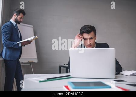 Zwei ernsthafte Männer in Anzügen, die im Büro arbeiten Stockfoto