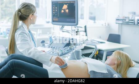 Im Krankenhaus, schwangere Frau bekommen Ultraschall-Sonogramm-Scan, Geburtshilfe erklärt ihr und ihrem unterstützenden Ehemann Verfahren. Frohe Familie Stockfoto