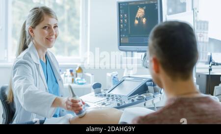 Im Krankenhaus, weibliche Geburtshelferin tun Ultraschall Screening einer schwangeren Mutter. Vater Unterstützt Fleißig Seine Schwangere Frau. Frohe Familie. Stockfoto