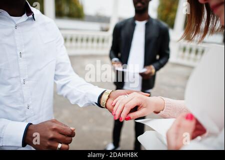 Hochzeit Verlobungszeremonie mit Pastor. Multiethnische Paare stellen sich gegenseitig klingeln. Beziehungen von afrikanischem Mann und weißer europäerin. Stockfoto