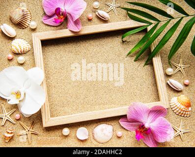 Sommer Strand Dekoration: Rahmen mit Orchideen, Muscheln und Seesterne auf Sand Hintergrund Stockfoto