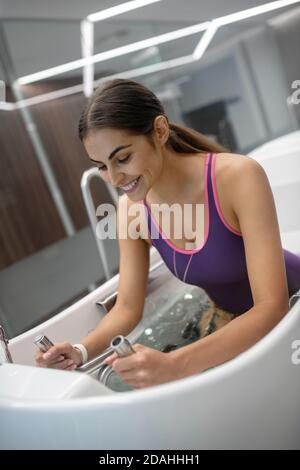 Aufgeregt dunkelhaarige Frau in lila Badeanzug mit Hydromassage Stockfoto