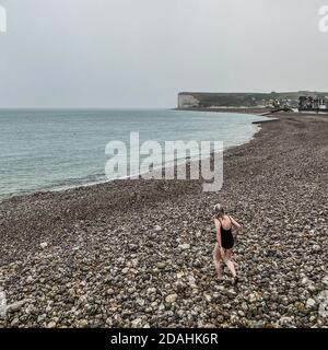 Nicht erkennbare Schwimmerin geht schwimmen im Meer im Regen, Opal-Küste, Normandie, Frankreich Stockfoto