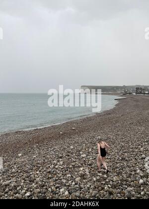 Nicht erkennbare Schwimmerin geht schwimmen im Meer im Regen, Opal-Küste, Normandie, Frankreich Stockfoto