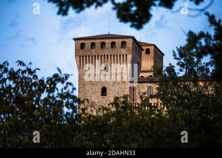 Panoramasicht auf Schloss Torrechiara durch Baumzweig bei einem bewölkten Sonnenuntergang, Parma, Italien Stockfoto