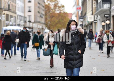 München, Deutschland. November 2020. Maskenpflicht in den Fußgängerzonen und öffentlichen Plätzen in München am 11.11.2020. Junge Frau mit Alltagsmaskentelefon mit Smartphone, Menschen gehen mit Gesichtsmasken, Maske durch die Innenstadt, Kaufinger Straße, Neuhauser Straße, MODEL RELEASED! Quelle: dpa/Alamy Live News Stockfoto