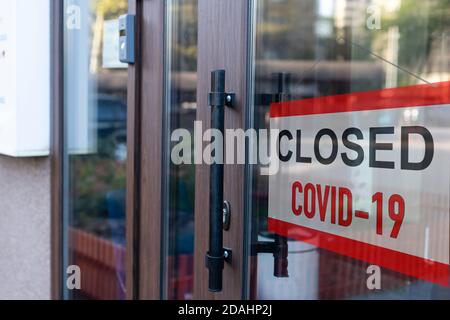 Nahaufnahme eines roten geschlossenen Schildes im Fenster von Ein Geschäft, in dem die Meldung aufgrund von Covid-19 geschlossen angezeigt wird Stockfoto