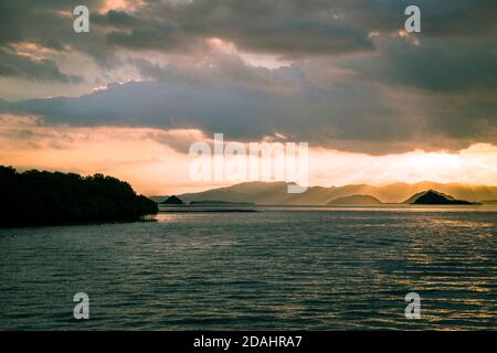 Malerische Aussicht auf Mangroven Silhoutte und Insel im tropischen pazifik bei einem bewölkten Sonnenuntergang, Komodo Indonesia Stockfoto