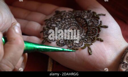 Nahaufnahme Makro-Aufnahme von Mehendi Henna Tattoo angewendet In einem komplizierten Muster auf der Hand einer Frau Mit sanftem Tageslicht und auf einem Rot Stockfoto