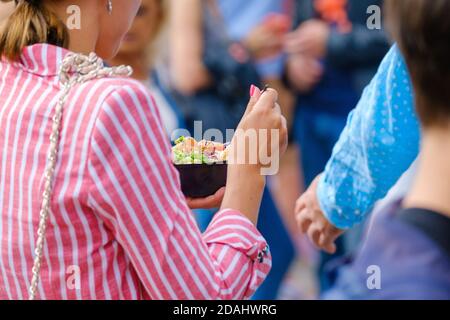 Crop Frau essen Salat in der Menge Stockfoto