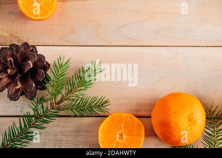 Weihnachtliche Einrichtung. Tannenzweige, Zapfen und Mandarinen auf einem hölzernen Hintergrund. Stockfoto