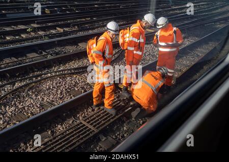 Von einem vorbeifahrenden Waggonfenster aus gesehen, inspiziert eine Ingenieursmannschaft am 12. November 2020 in London, England, die Bahnausrüstung vor dem Waterloo-Hauptbahnhof. Stockfoto