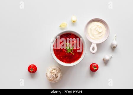 Hausgemachte traditionelle ukrainische Rübensuppe mit frischem grünen Dill. Russische Borscht in Schüssel mit Tomaten, saure Sahne, und Pilze auf weißem Hintergrund mit Kopierraum. Stockfoto