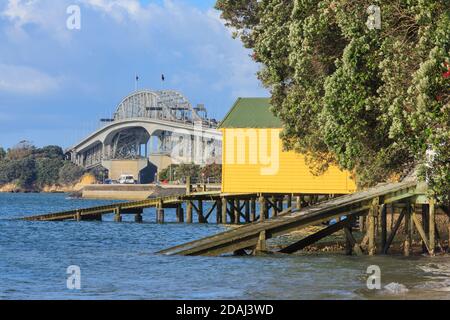 Die Auckland Harbour Bridge, Auckland, Neuseeland, mit Bootshäusern am Hamilton Road Beach im Vordergrund