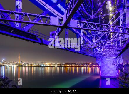 Die Skyline von Auckland, Neuseeland, bei Nacht, unter der Auckland Harbour Bridge Stockfoto